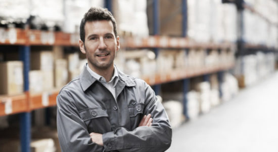Portrait of a handsome warehouse worker smiling with his arms folded